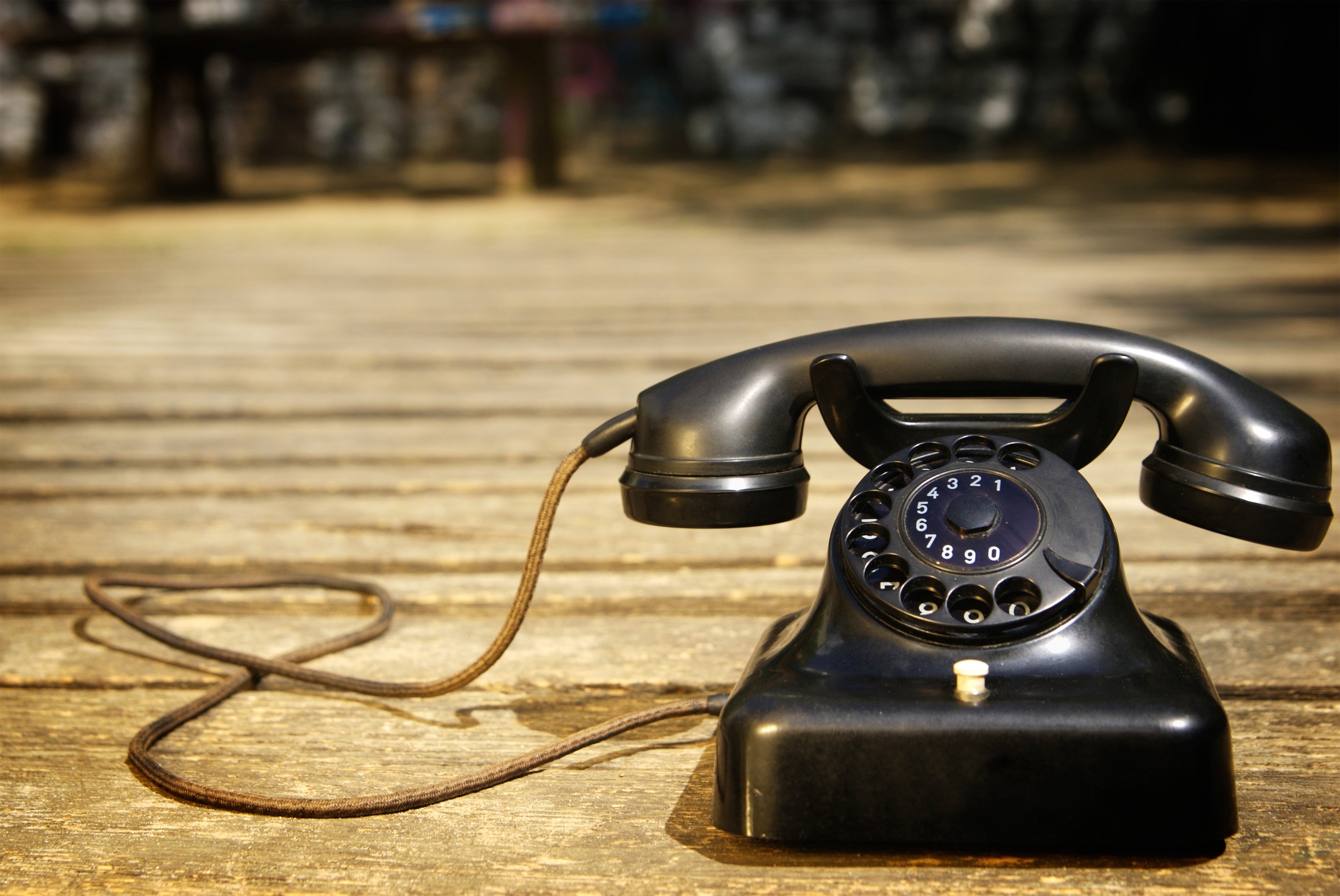Old rotary dial telephone on a wooden desk representing how businesses abandon Plain Old Telephone Service (POTS) for modern VoIP systems
