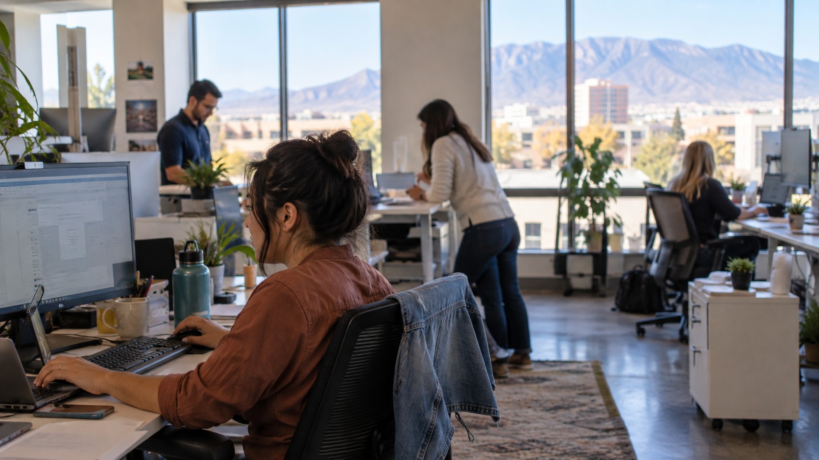 Team working at computers in a bright Albuquerque office with mountain views